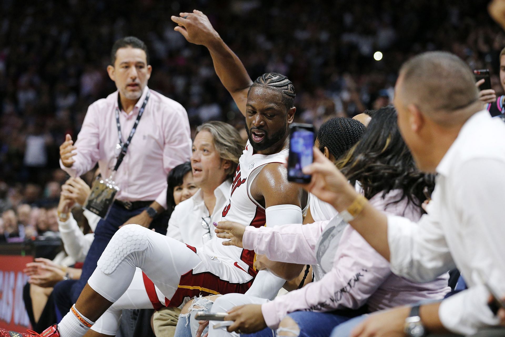 Dwyane Wade #3 of the Miami Heat falls into the fans after shooting a three pointer against the Philadelphia 76ers during the second half at American Airlines Arena on April 09, 2019 in Miami, Florida