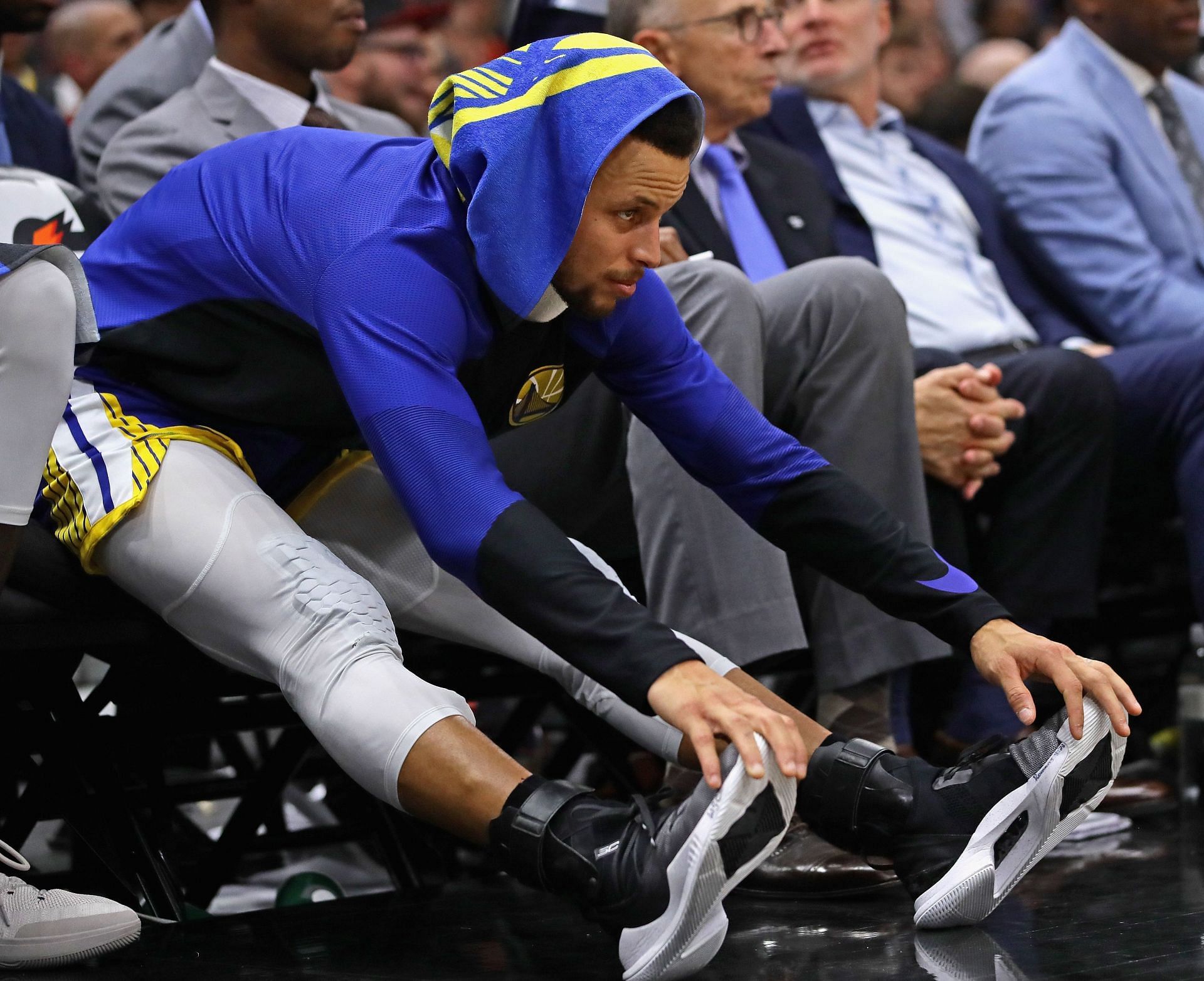Steph Curry of the Golden State Warriors stretches on the bench in 2018