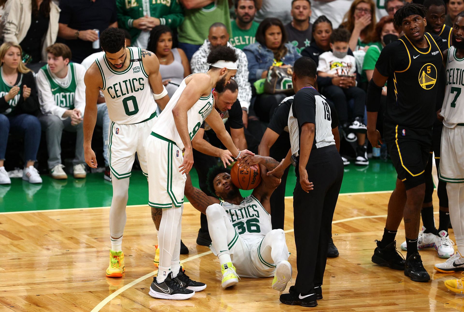 Marcus Smart of the Boston Celtics sits up with help from teammates